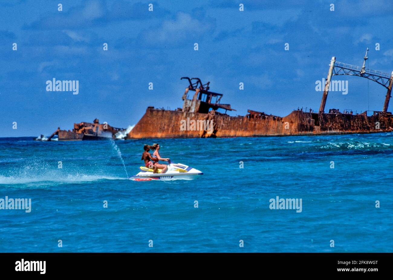 Dominikanische Republik, Wassermoped mit Urlaubern und Schiffsrack, vor der Kueste von Punta Cana. Stockfoto