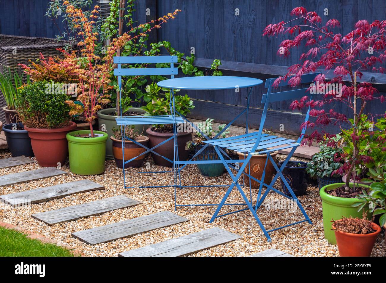 Blaues Bistro in einem Garten umgeben von Sträuchern und acers Stockfoto