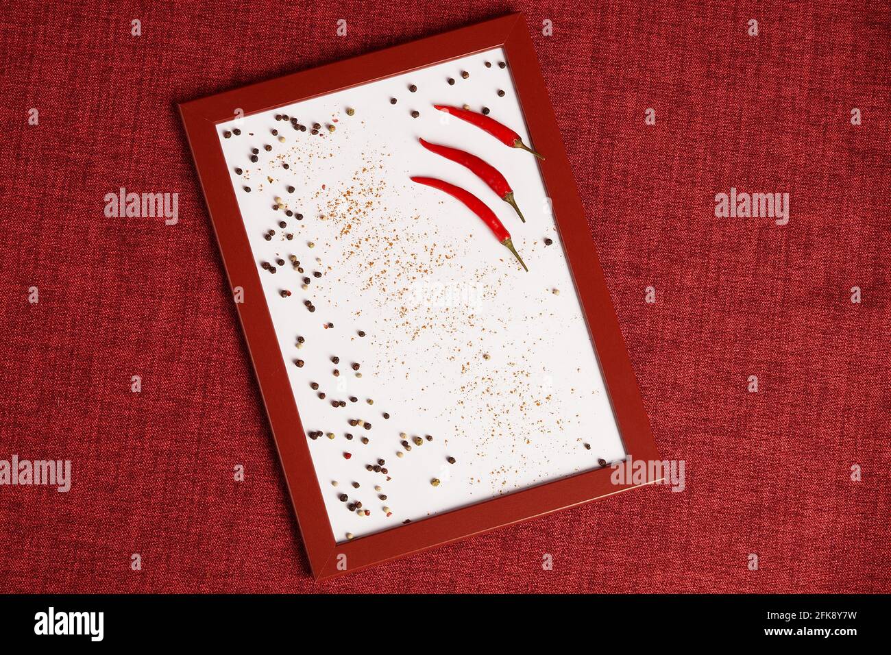 Foto eines roten Chilischoten in einem Rahmen. Gewürze zum Kochen auf dem Foto. Stockfoto
