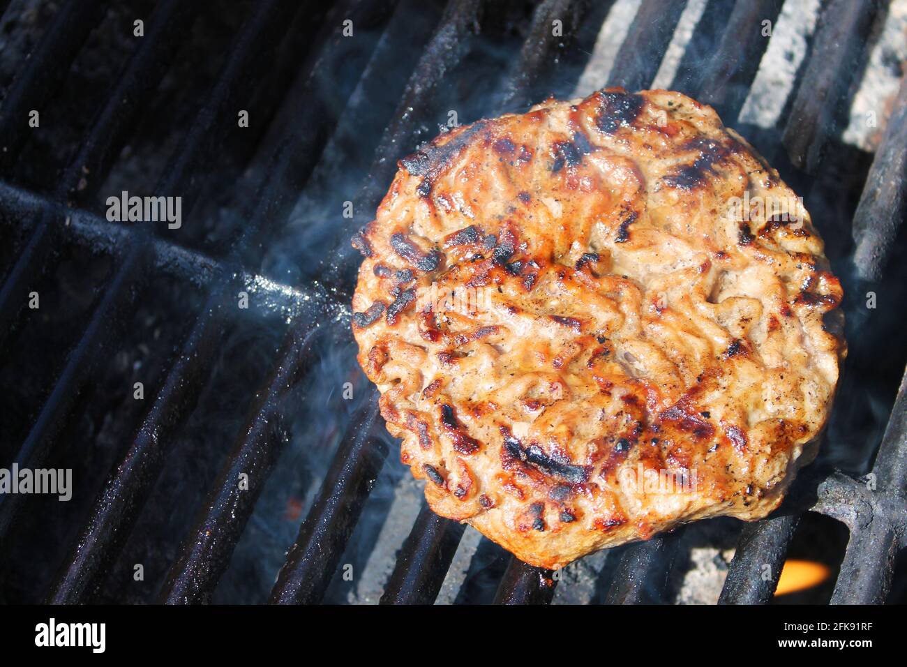 Nahaufnahme eines Hamburgerpastys beim Kochen auf einem Barbecue-Grill. Stockfoto