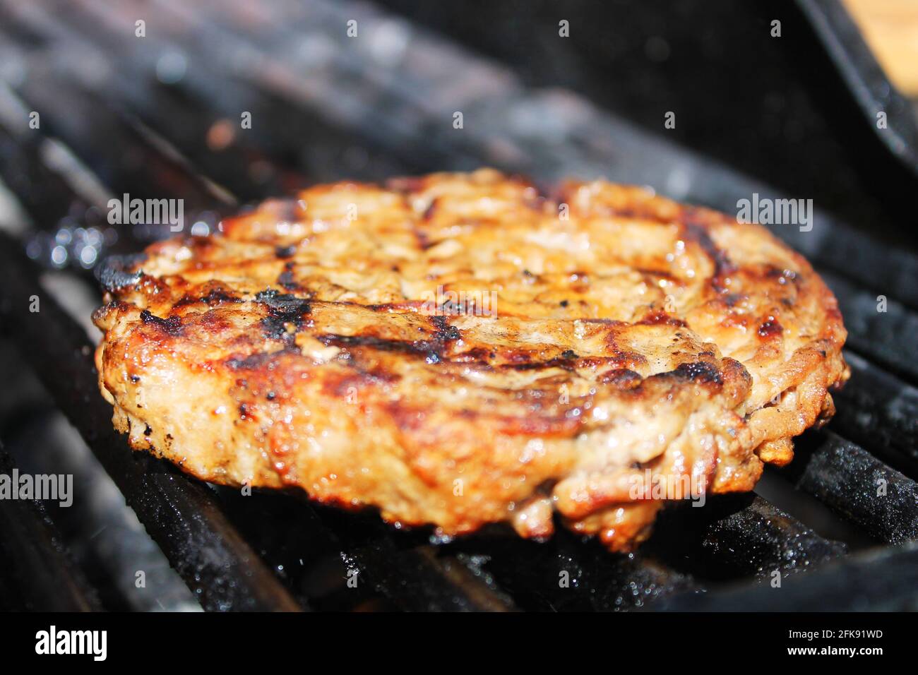 Nahaufnahme eines Hamburgerpastys beim Kochen auf einem Barbecue-Grill. Stockfoto