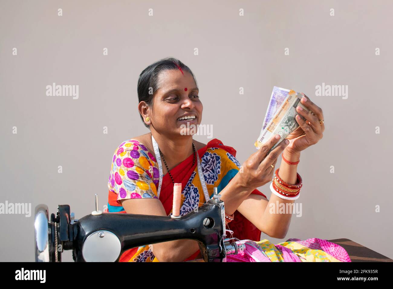PORTRÄT EINER LÄNDLICHEN FRAU mit Nähmaschine und Zählung Geld Stockfoto