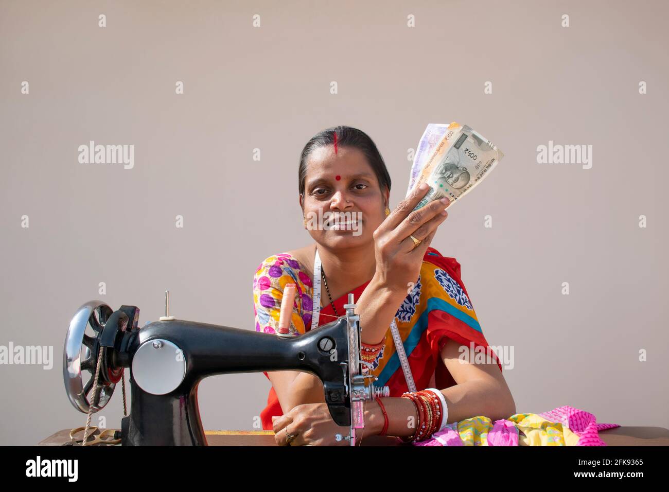 PORTRÄT EINER LÄNDLICHEN FRAU mit Nähmaschine und Zählung Geld Stockfoto
