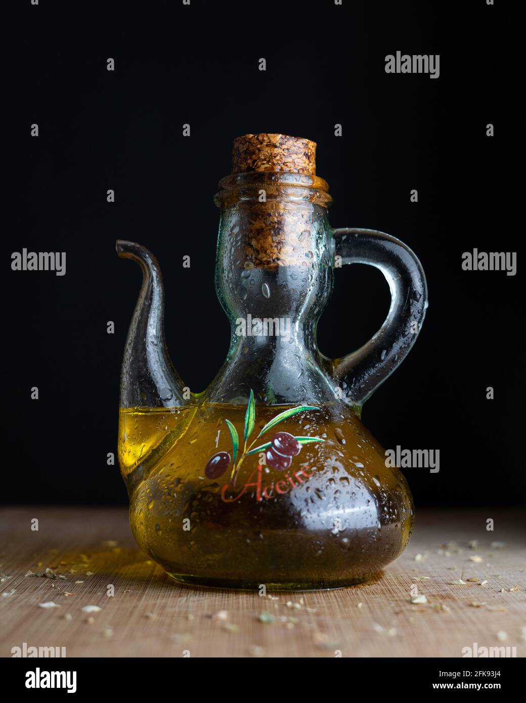 Eine Glasflasche, die extra natives Olivenöl aus Spanien enthält und von Oregano umgeben ist. (Übersetzung 'Aceite': 'Öl') Stockfoto
