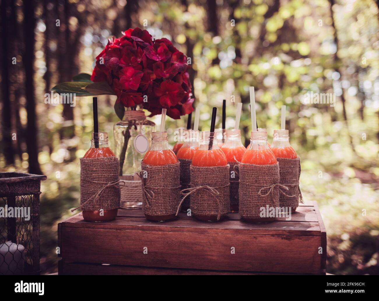 Flaschen Saft und rote Blumen auf dem rustikalen Tisch. Vintage Sommer  Hochzeit Tischdekoration Stockfotografie - Alamy
