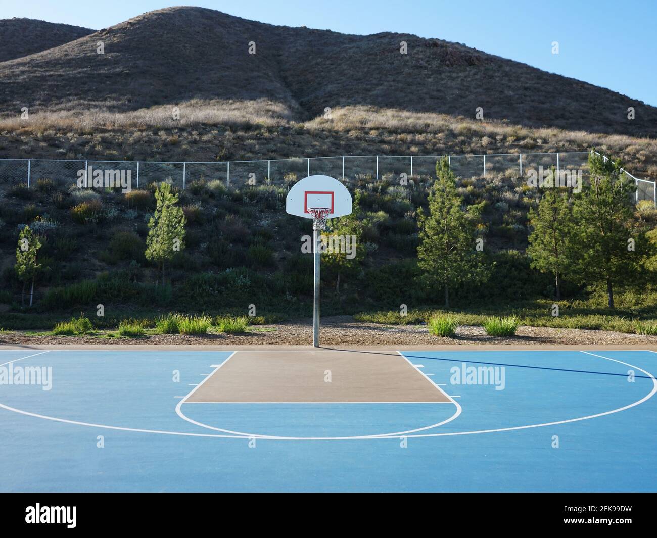 Halber Hof Blick auf den öffentlichen Basketballplatz mit Hügeln in Hintergrund Stockfoto