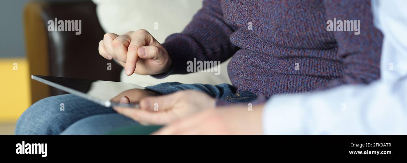 Mann und Frau sitzen auf der Couch und schauen hinein Digitales Tablet Stockfoto