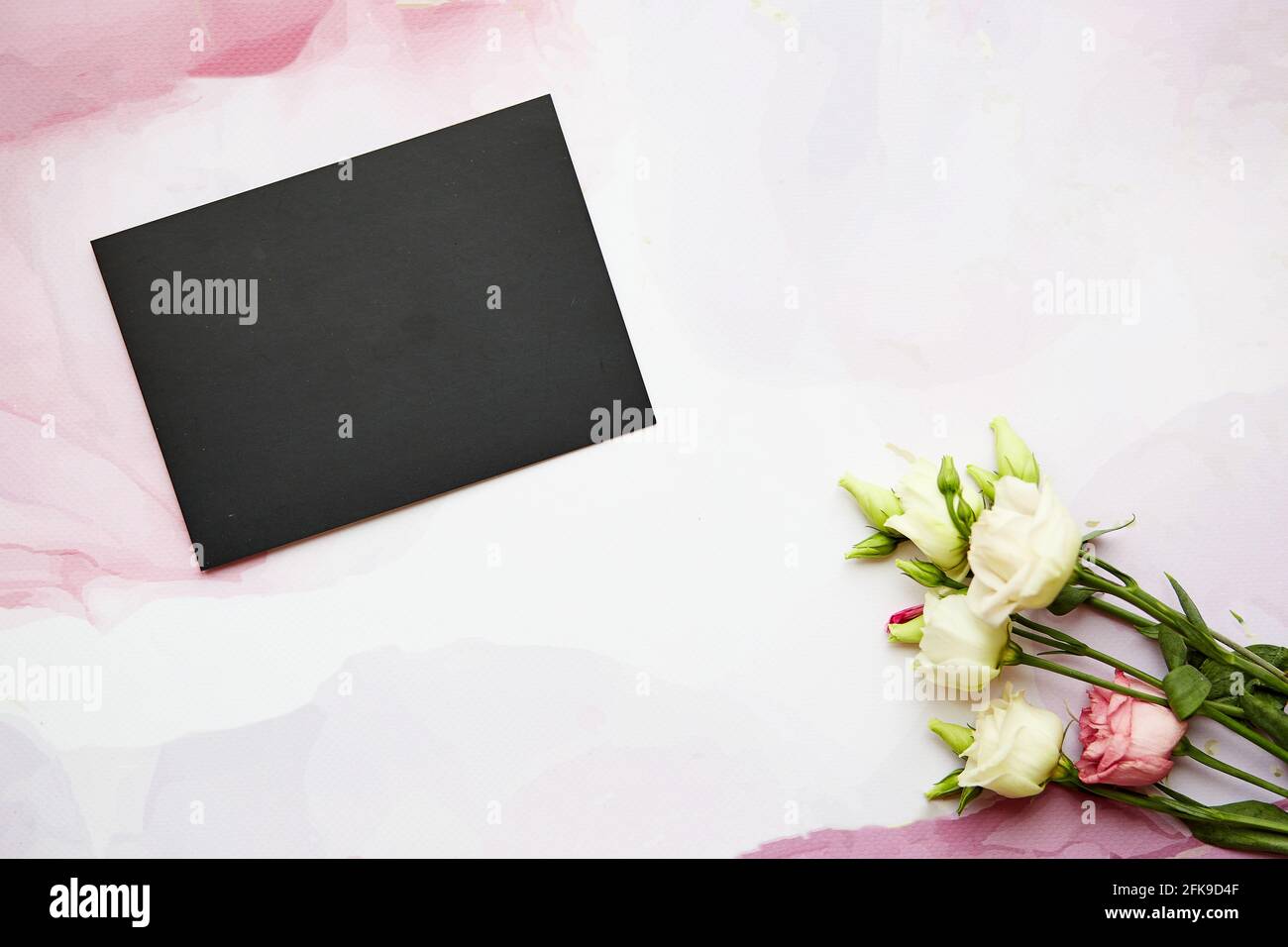 Stiller Sommer Schreibwaren Stillleben auf rosa fließende Oberfläche. Rosa und weiße Eustona-Blüten. Leere Grußkarte – Nachbau der Szene. Stockfoto