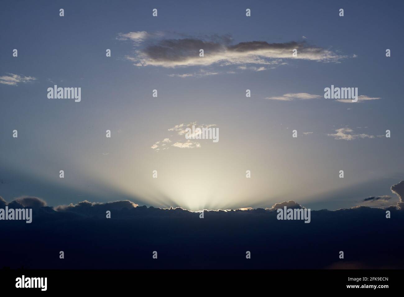 Die letzten Sonnenstrahlen schauen von hinten heraus Eine schwarze Wolke in einem bewölkten Himmel Stockfoto