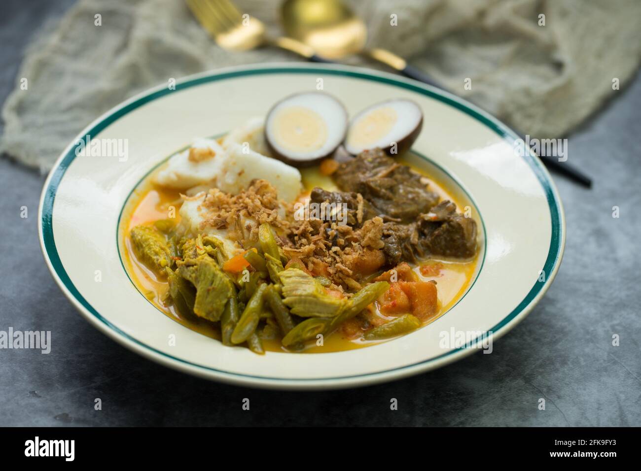 Ketupat oder lontong sayur, indonesische Küche, spezielles Gericht, das bei der Eid Mubarak/Eid Fitr-Feier serviert wird. Stockfoto