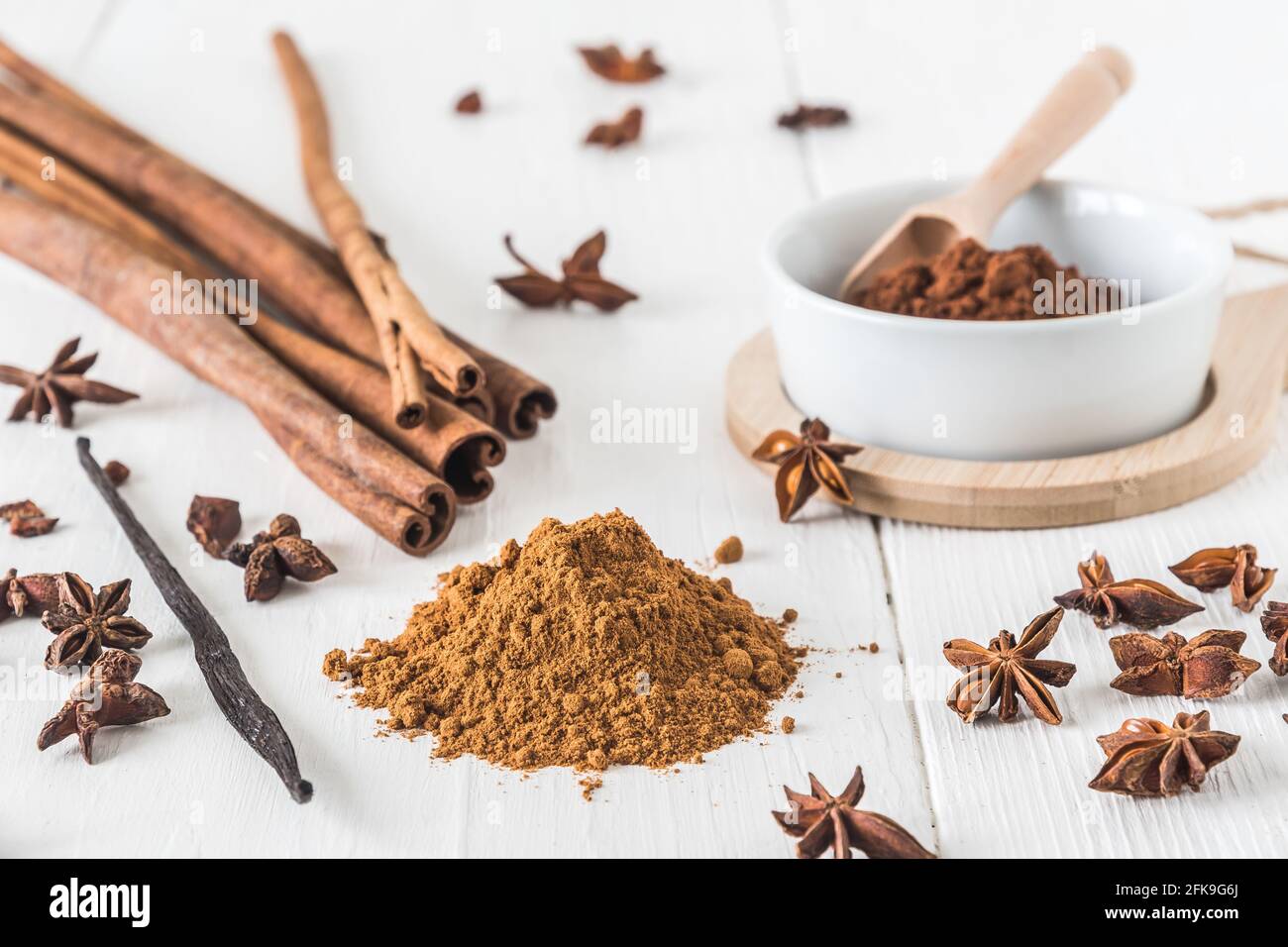 Backen von Gewürzen wie Zimt, Sternanise und Kakao auf weißem Holztisch Stockfoto