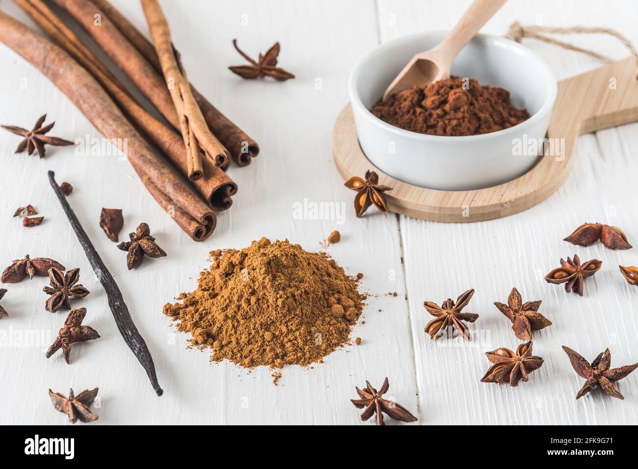 Backen von Gewürzen wie Zimt, Sternanise und Kakao auf weißem Holztisch Stockfoto