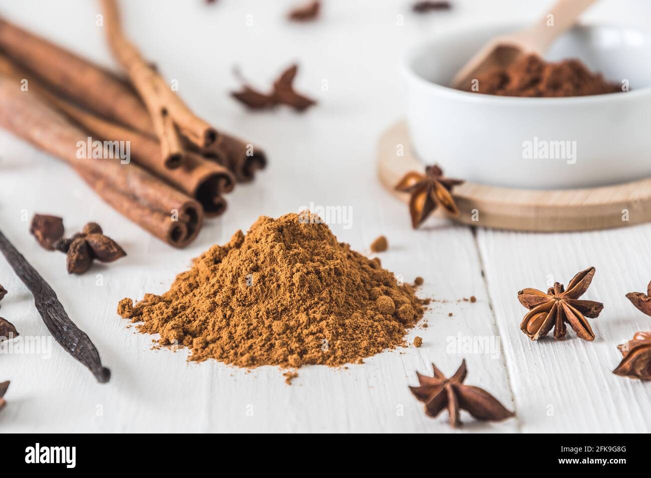 Backen von Gewürzen wie Zimt, Sternanise und Kakao auf weißem Holztisch Stockfoto