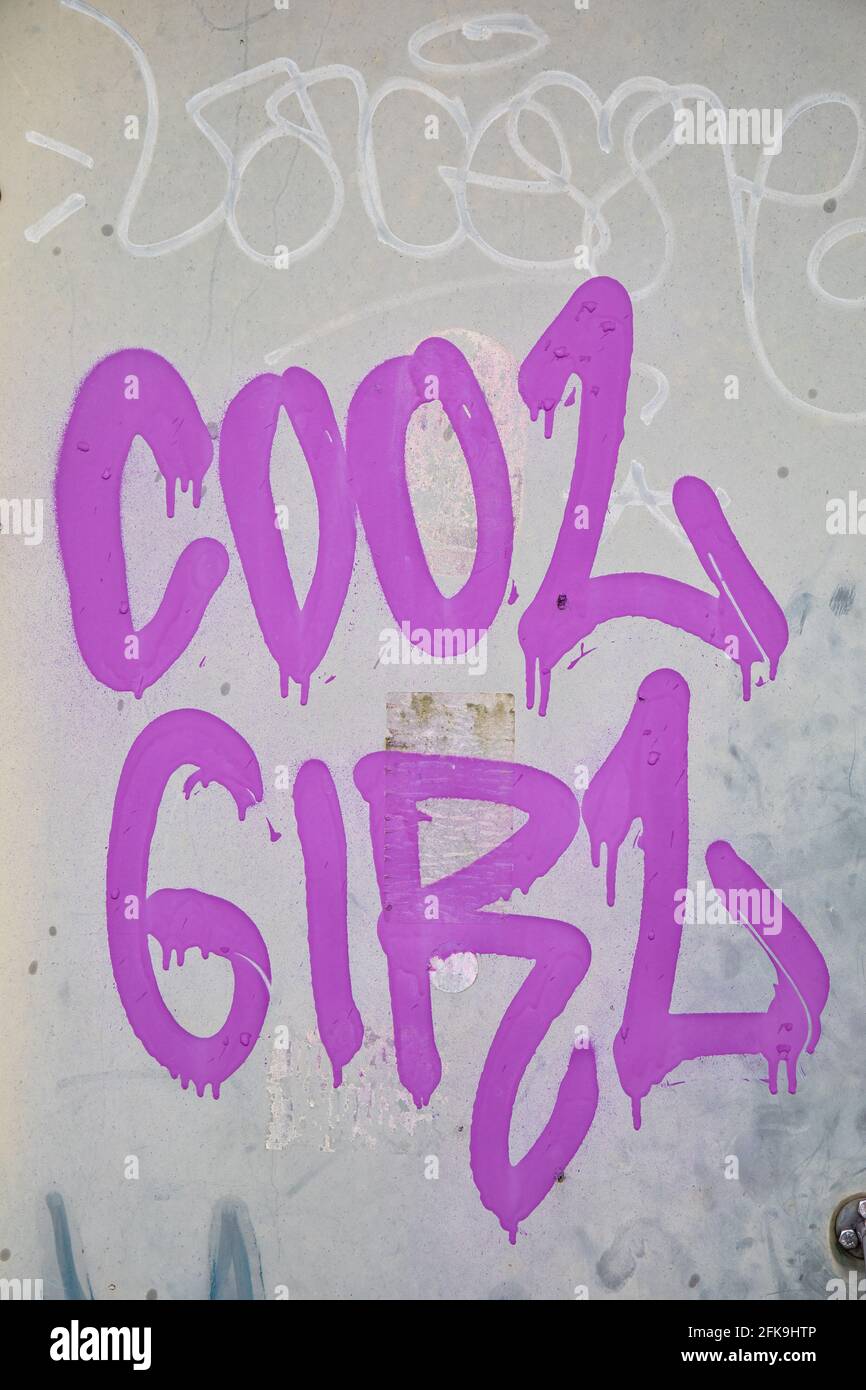 Cooles Mädchen. Hellviolette Graffiti oder Tags auf grauem Hintergrund. Stockfoto