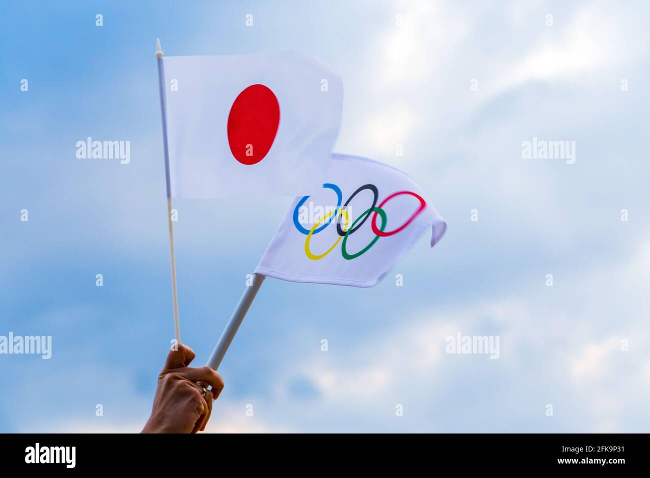 Fan winkt die Nationalflagge Japans und die olympische Flagge mit Symbol-olympischen Ringen. Stockfoto