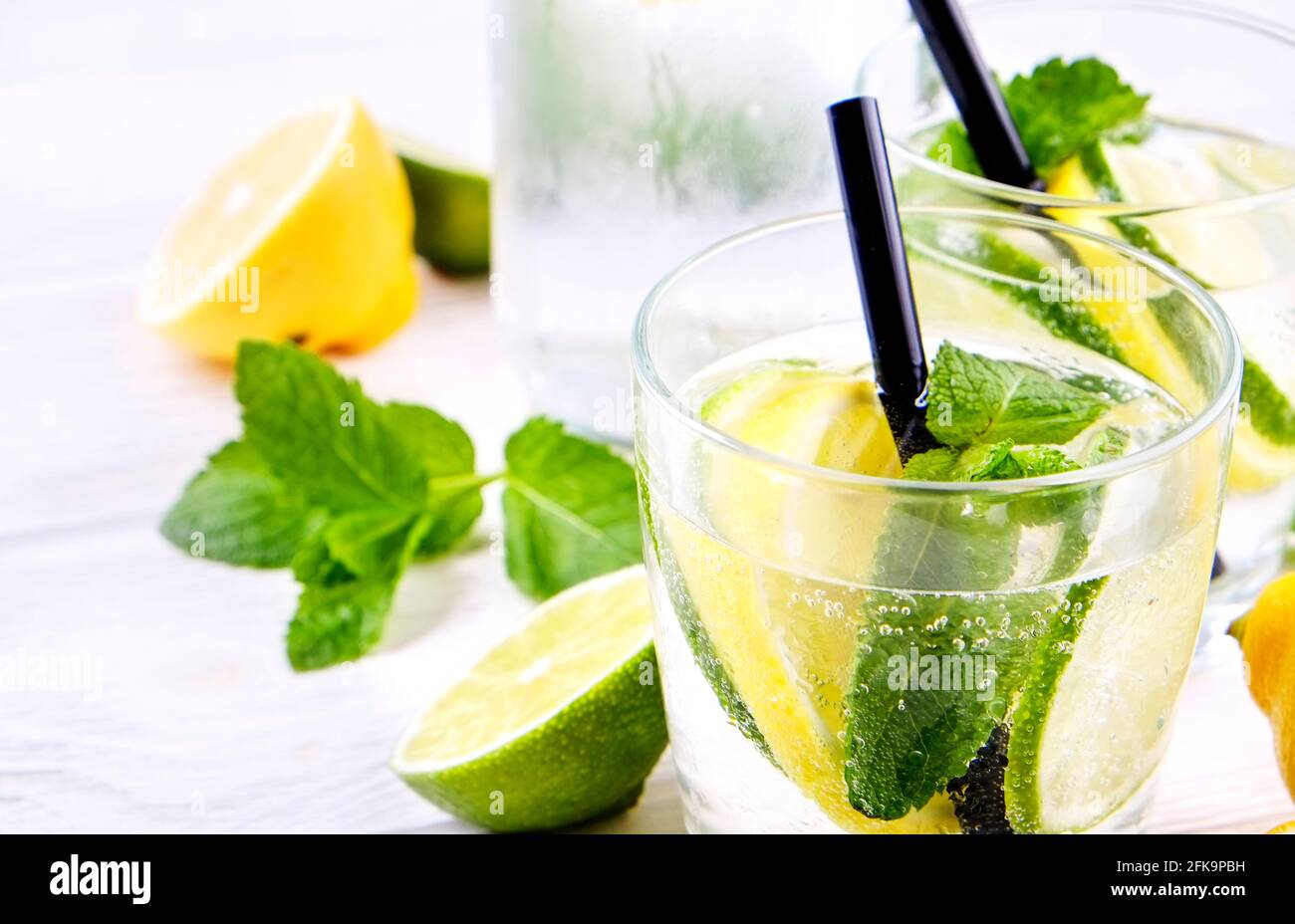Vintage-Flasche mit zwei Gläsern erfrischender alkoholfreier Mojito-Limonade, Sekt mit Zitrone, Limettenscheiben, Minzblättern, Stroh, Holz Stockfoto