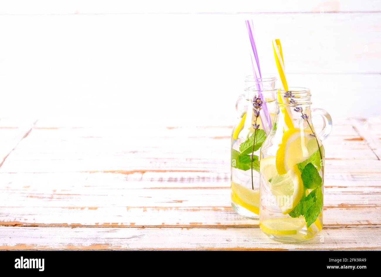 Eiskalte Lavendellimonade, Zitrone, Stroh. Zwei klassische Mojito-Drinks, alkoholfreier Cocktail mit Eis in zwei Vintage-Hipster-Flaschen, auf grunged Stockfoto