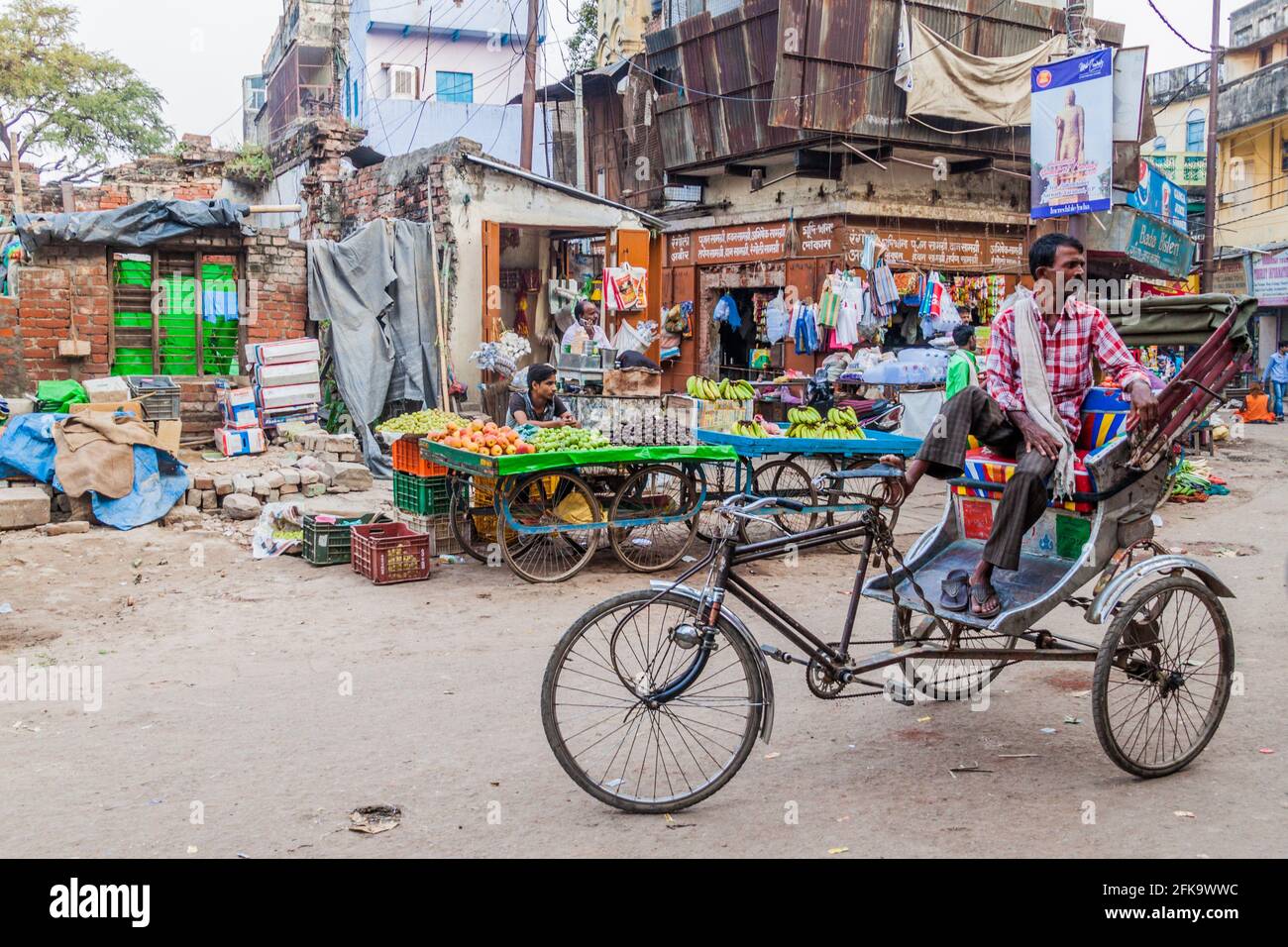 VARANASI, INDIEN - 25. OKTOBER 2016: Straßenobststände und eine Rikscha-Rikscha in Varanasi, Indien Stockfoto