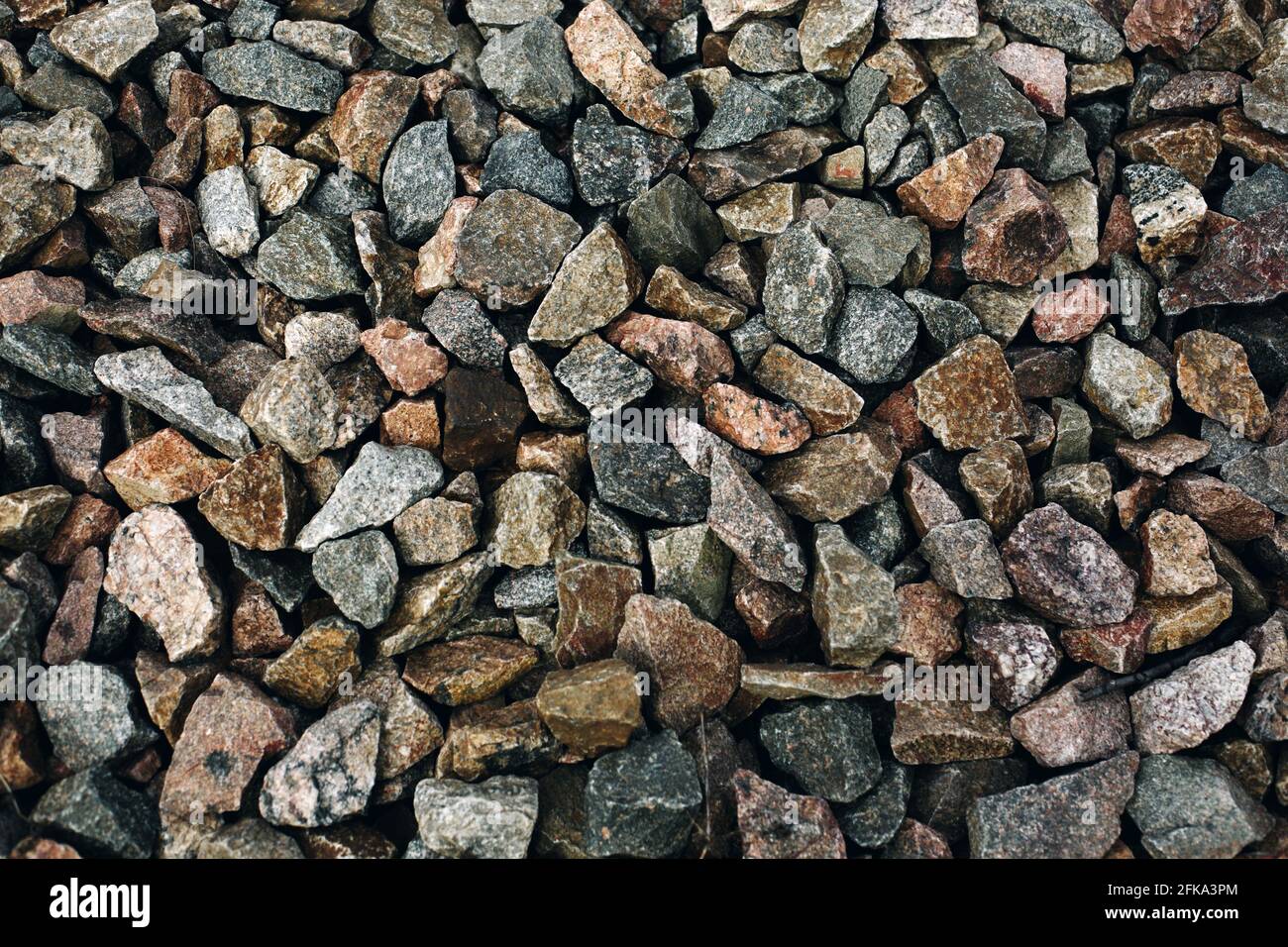 Alte bunte Steine rauer Hintergrund, viele Felsen in der Nähe der Bahnstrecke Stockfoto