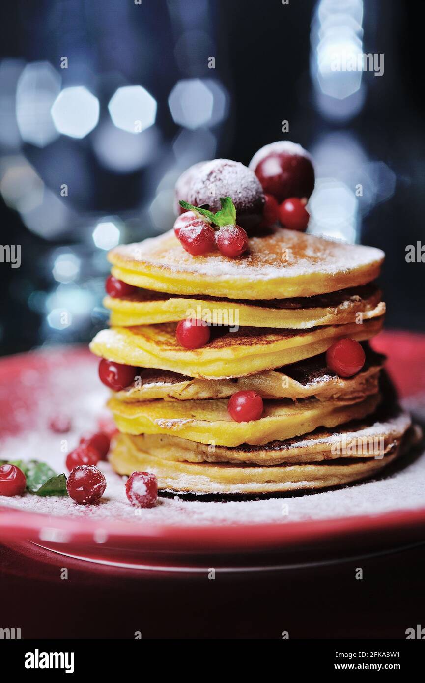 Stapel von Pfannkuchen mit frischen Beeren und Zuckerpulver auf Rote Platte Stockfoto