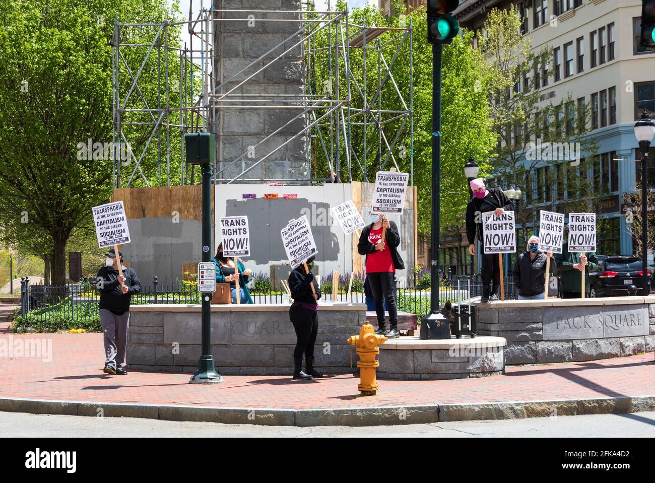 ASHEVILLE, NC, USA-25 APRIL 2021: Acht Covid-maskierte Menschen auf dem Pack Square halten Schilder mit der Aufschrift „Trans Rights Now“ und prosozialistische Botschaften. Stockfoto