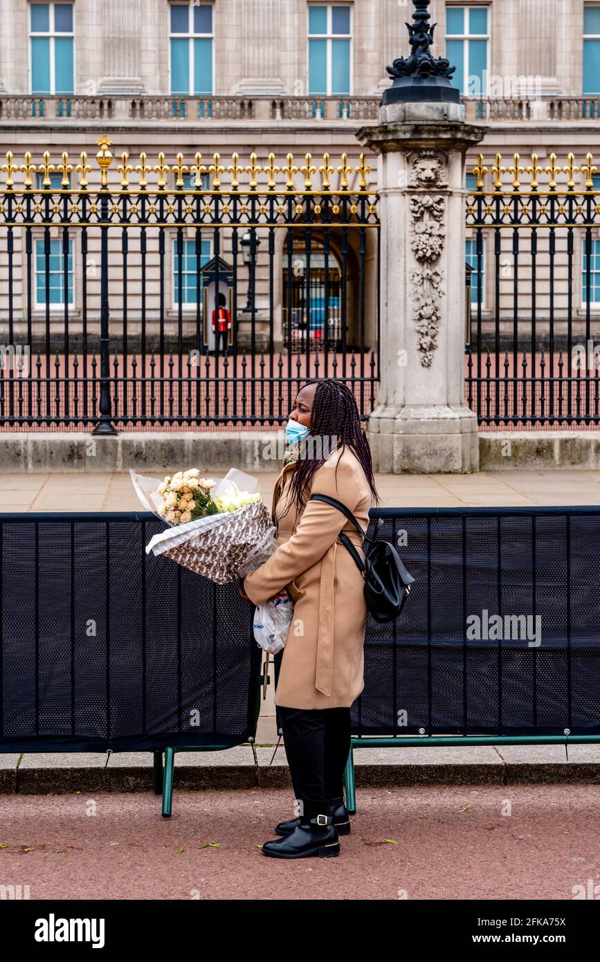 Eine junge Frau wartet darauf, Blumen vor den Toren des Buckingham Palace zu legen, um Prinz Philip (dem Herzog von Edinburgh, London, Großbritannien) zu erinnern. Stockfoto