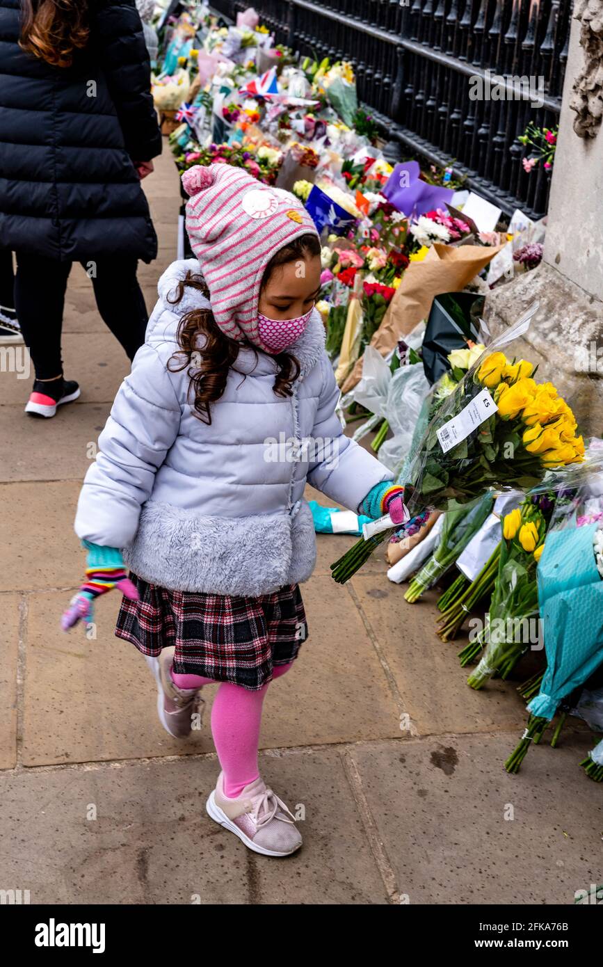 Ein Kind legt Blumen vor den Buckingham Palace in Erinnerung an Prinz Philip (der Herzog von Edinburgh), der kürzlich verstorben war, London, Großbritannien. Stockfoto