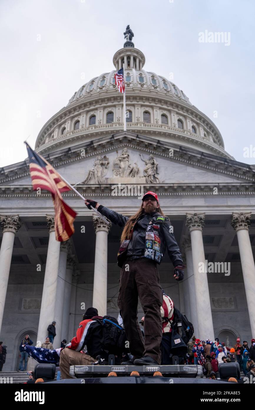 Washington DC, USA. Januar 2021. Während des Sturms des Gebäudes durch Trump-Anhänger winkt ein Mann vor dem Kapitolgebäude eine Flagge. Stockfoto