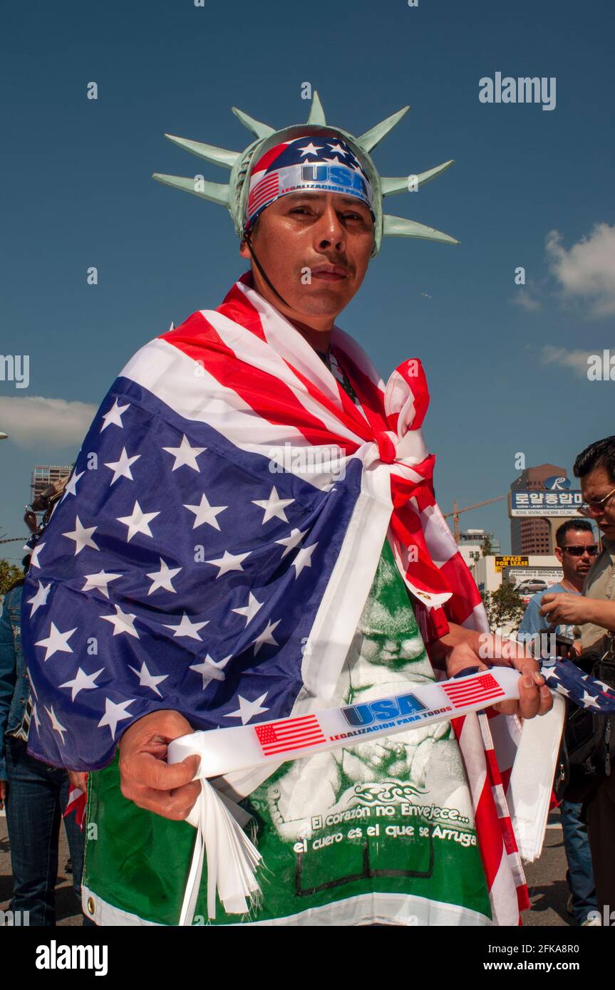 Ein patriotischer Mann mit amerikanischen Flaggen und einer Lady Liberty-Krone posiert für ein Bild bei einem Protest gegen die Einwanderungsrechte in Downtown Los Angeles. Stockfoto