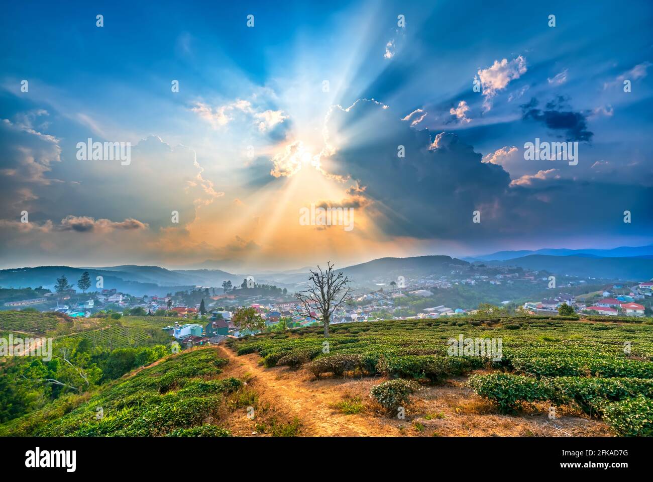 Blick auf den Sonnenuntergang im Hochland mit dramatischem Himmel und Schönes kleines Dorf in der Ferne, um ein friedliches Ende Tag Stockfoto