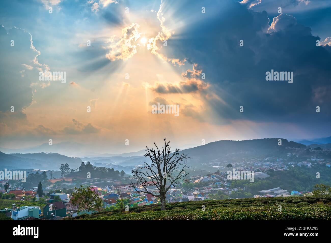 Blick auf den Sonnenuntergang im Hochland mit dramatischem Himmel und Schönes kleines Dorf in der Ferne, um ein friedliches Ende Tag Stockfoto