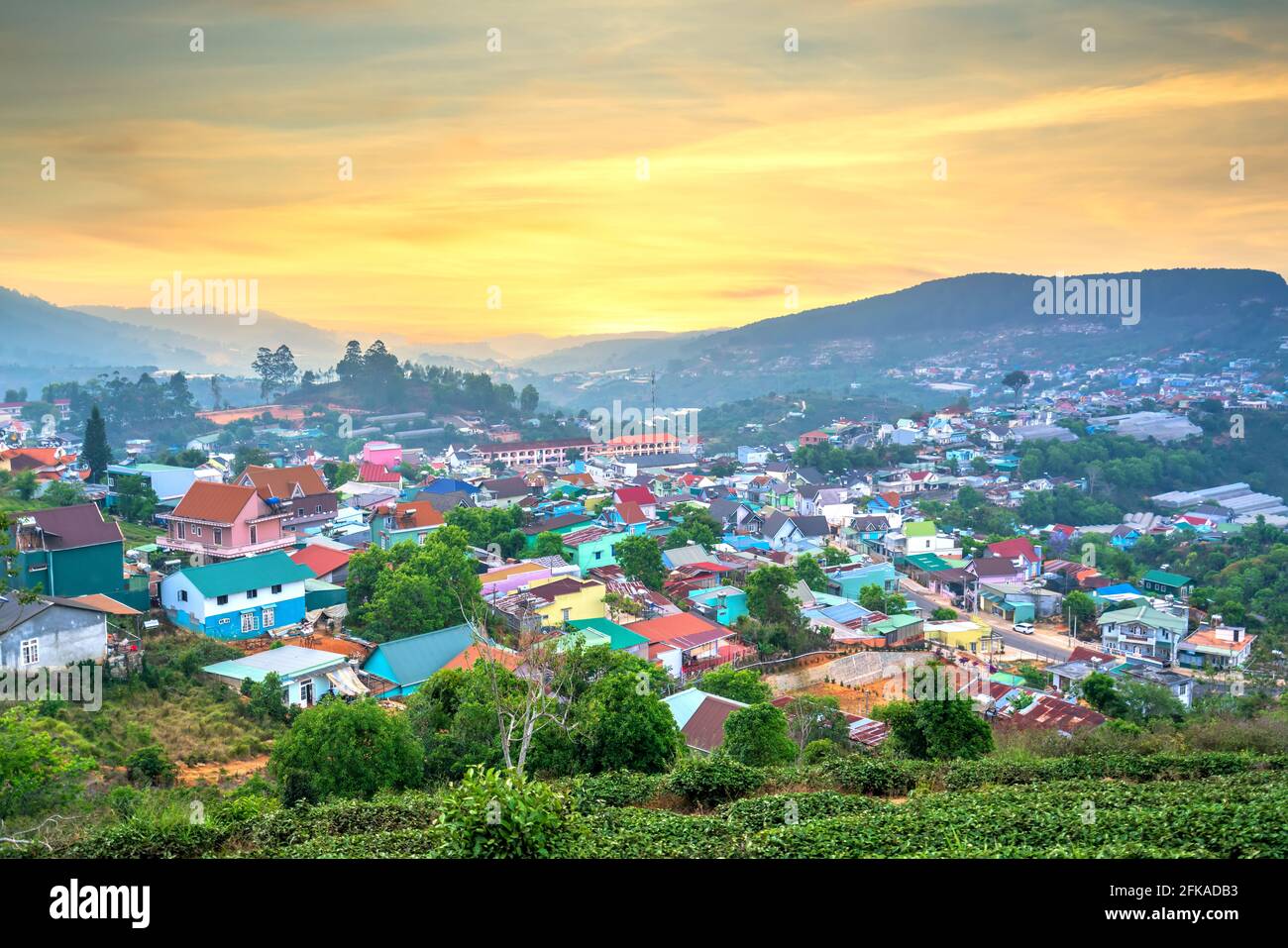 Blick auf den Sonnenuntergang im Hochland mit dramatischem Himmel und Schönes kleines Dorf in der Ferne, um ein friedliches Ende Tag Stockfoto