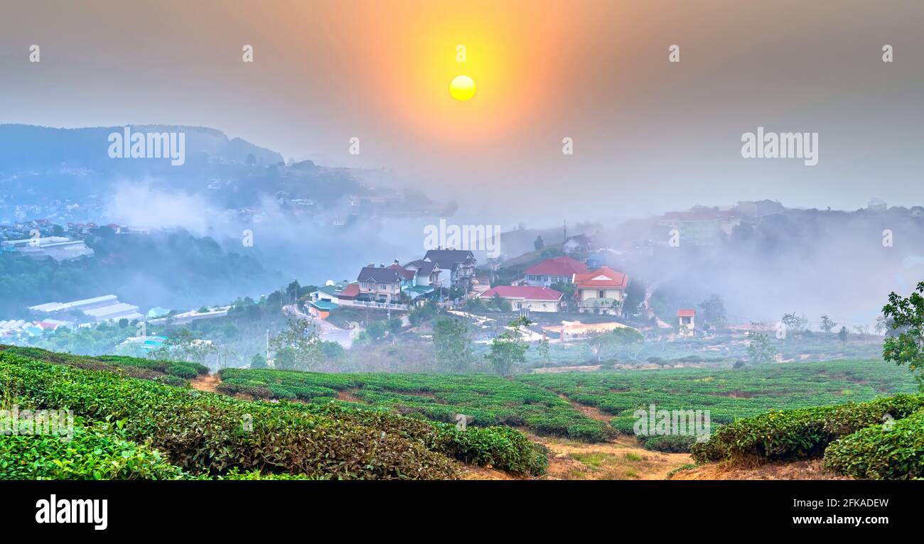 Blick auf den Sonnenuntergang im Hochland mit dramatischem Himmel und Schönes kleines Dorf in der Ferne, um ein friedliches Ende Tag Stockfoto