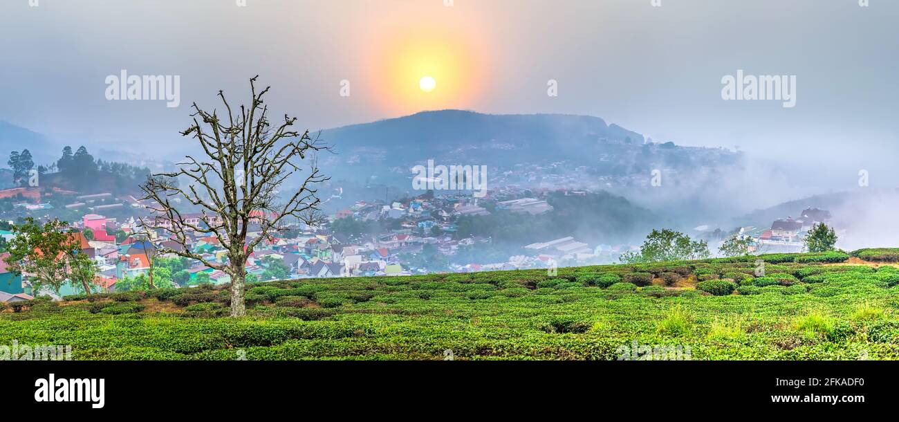 Blick auf den Sonnenuntergang im Hochland mit dramatischem Himmel und Schönes kleines Dorf in der Ferne, um ein friedliches Ende Tag Stockfoto