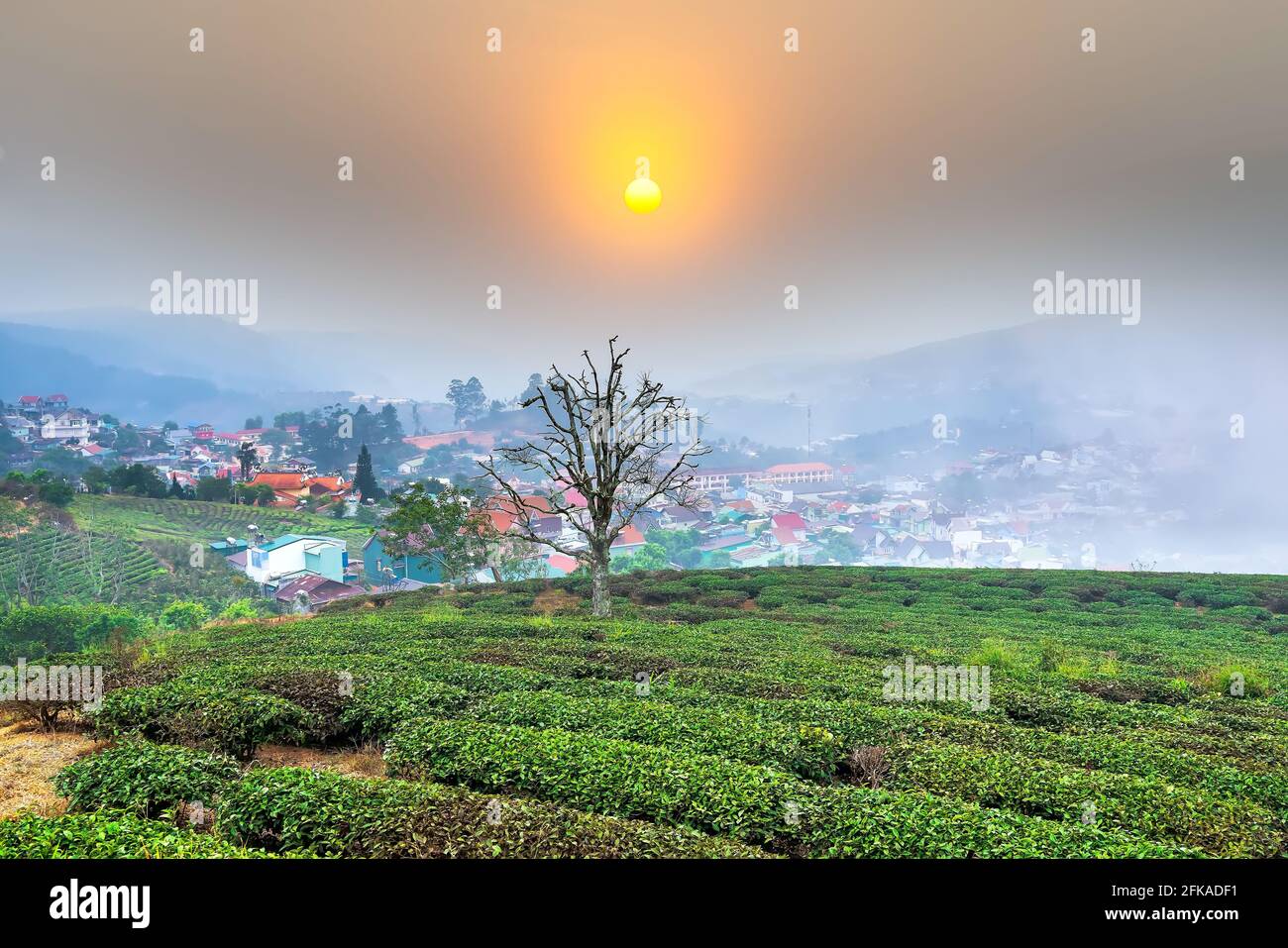 Blick auf den Sonnenuntergang im Hochland mit dramatischem Himmel und Schönes kleines Dorf in der Ferne, um ein friedliches Ende Tag Stockfoto