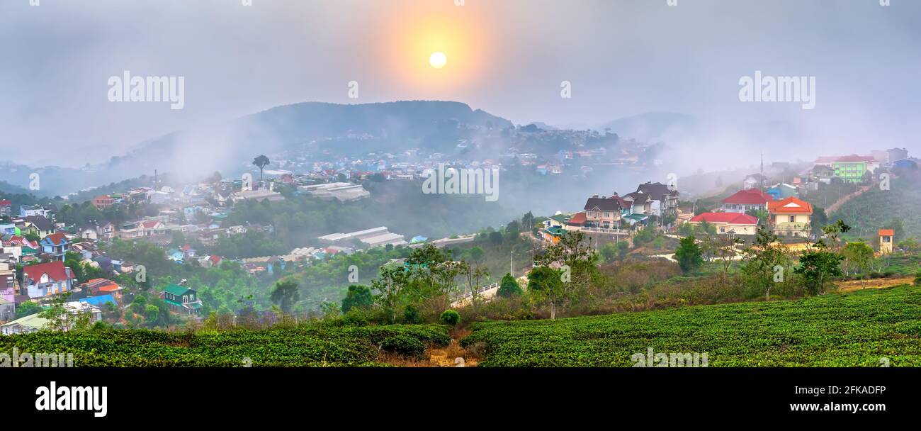 Blick auf den Sonnenuntergang im Hochland mit dramatischem Himmel und Schönes kleines Dorf in der Ferne, um ein friedliches Ende Tag Stockfoto