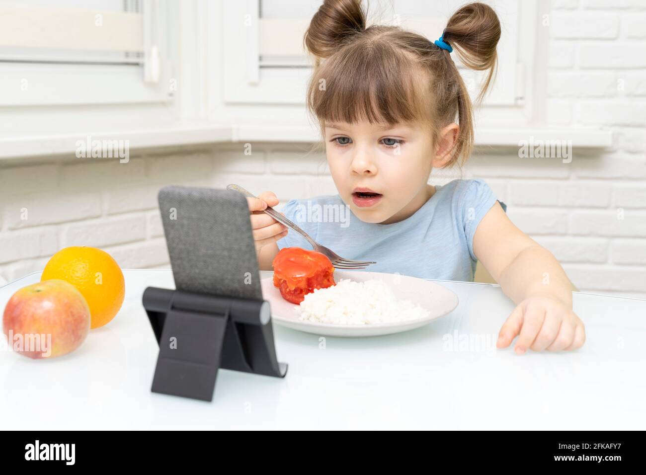 Kind Mädchen Essen und beobachten Cartoons auf einem Smartphone Stockfoto