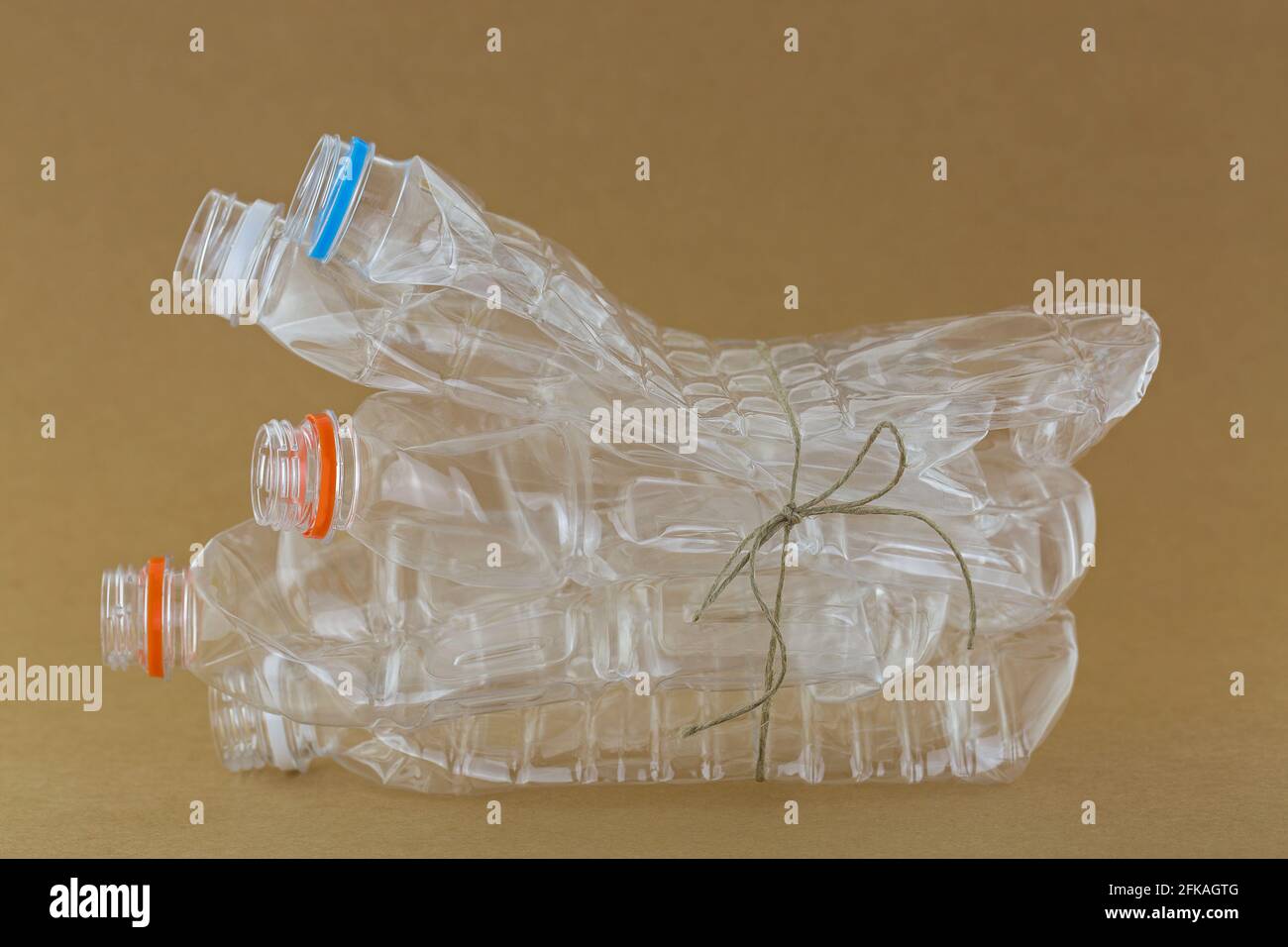 Stapel leerer, recycelbarer, klarer Kunststoff-Mineralwasser-Flaschen Auf braunem Hintergrund zusammengebunden Stockfoto