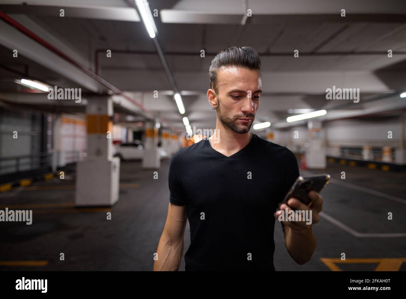 Schöner Mann in der Nacht auf dem Parkplatz mit Handy Stockfoto