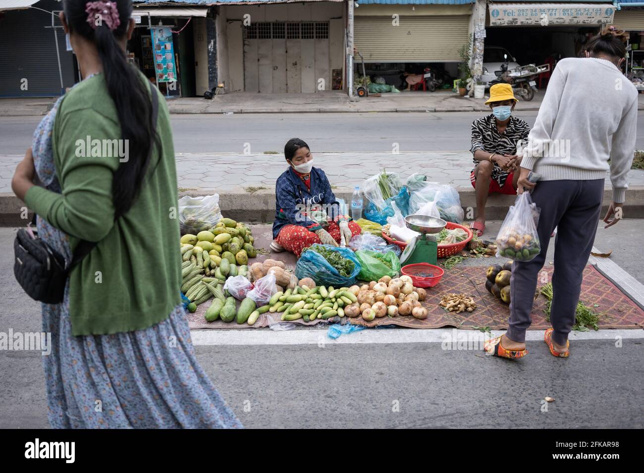 Phnom Penh, Kambodscha. April 2021. In einer Roten Zone in Steung Meanchey wird ein sozial distanzierter Markt am Straßenrand eingerichtet.Phnom Penh befindet sich weiterhin im Lockdown, da Kambodscha drastische Maßnahmen ergreift, um die Ausbreitung seines bisher schlimmsten COVID-19-Ausbruchs zu verringern. Die Sperre hat viele von ihnen aus der Arbeit gezwungen, darunter Fabrikarbeiter und Marktverkäufer, was die ärmsten Bewohner der Städte in Schwierigkeiten gebracht hat oder nicht in der Lage ist, sich grundlegende Notwendigkeiten zu leisten. (Foto von Andy Ball/SOPA Images/Sipa USA) Quelle: SIPA USA/Alamy Live News Stockfoto