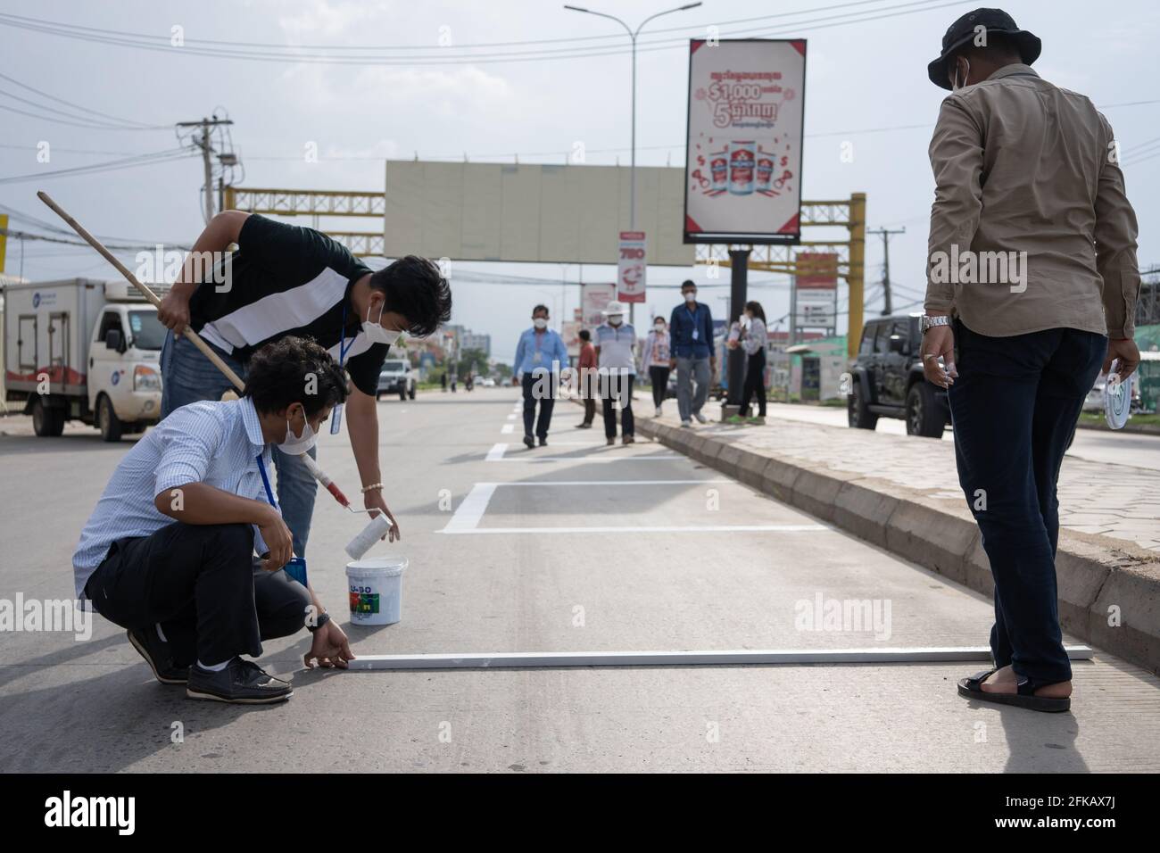 Phnom Penh, Kambodscha. April 2021. Regierungsbeamte malen Marker für Marktverkäufer als Teil eines sozial distanzierten Marktes in einer Roten Zone.Phnom Penh bleibt in der Sperre, da Kambodscha drastische Maßnahmen ergreift, um die Ausbreitung seines bisher schlimmsten COVID-19-Ausbruchs zu reduzieren. Die Sperre hat viele von ihnen aus der Arbeit gezwungen, darunter Fabrikarbeiter und Marktverkäufer, was die ärmsten Bewohner der Städte in Schwierigkeiten gebracht hat oder nicht in der Lage ist, sich grundlegende Notwendigkeiten zu leisten. Credit: Andy Ball/SOPA Images/ZUMA Wire/Alamy Live News Stockfoto