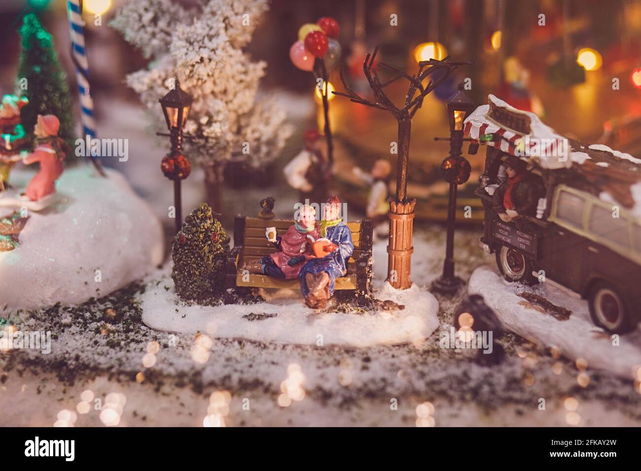 Traditionelles Miniatur-Weihnachtsdorf. Zwei Menschen sitzen am Silvesterabend auf einer Bank Stockfoto