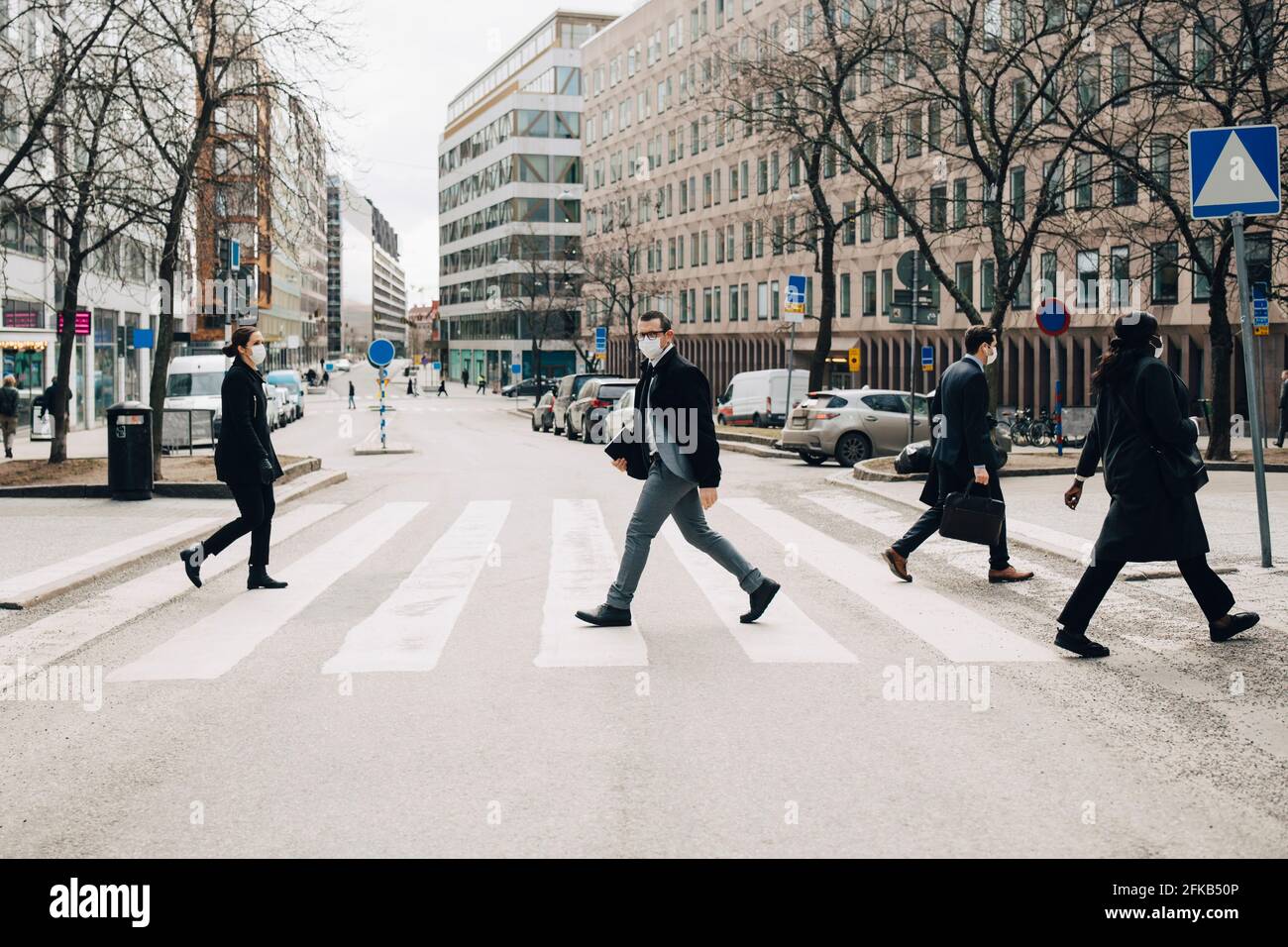 Geschäftsleute, die während einer Pandemie die Straße in der Stadt überqueren Stockfoto