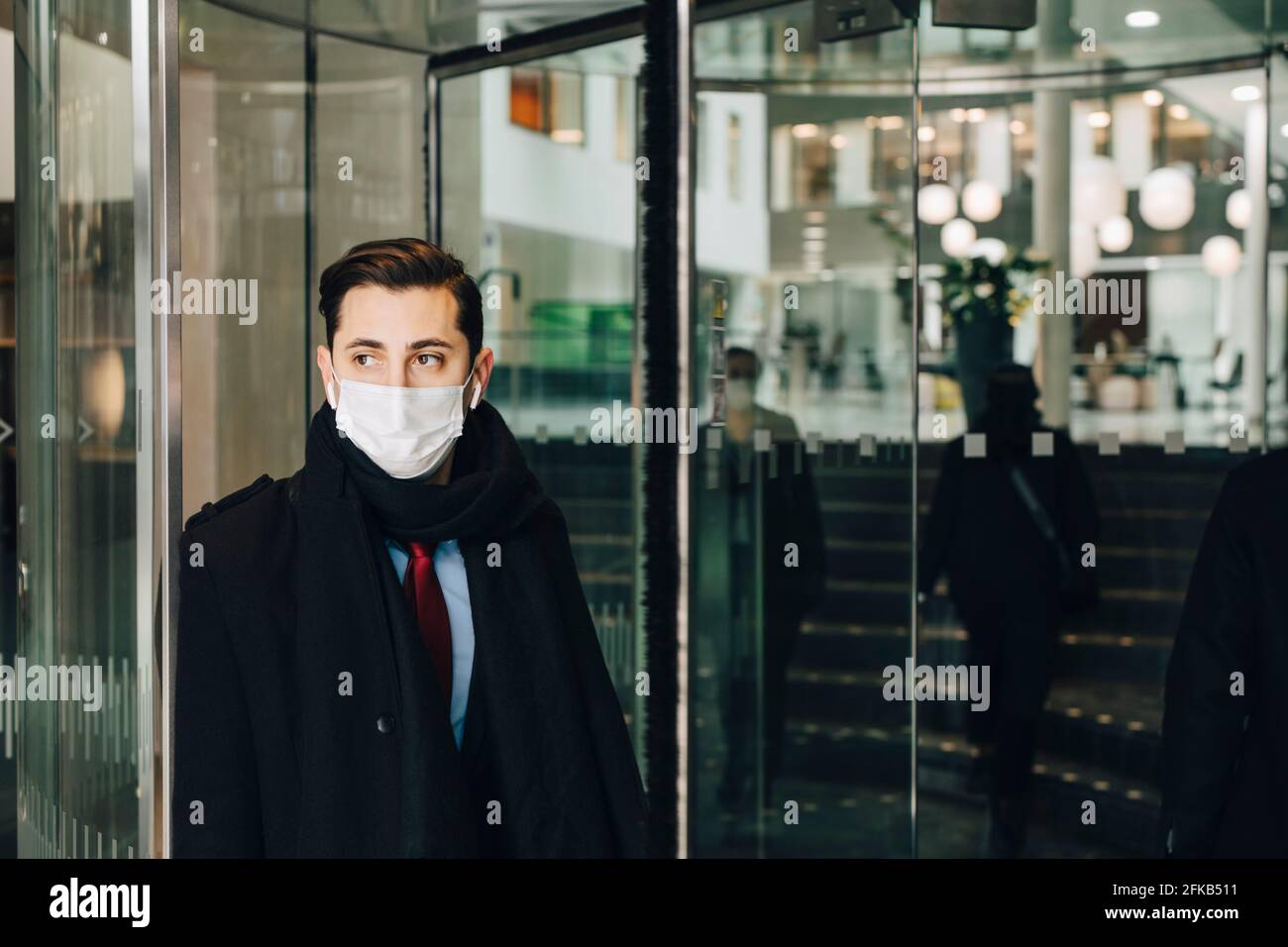Geschäftsmann, der während einer Pandemie an einer Glastür im Einkaufszentrum gelehnt ist Stockfoto