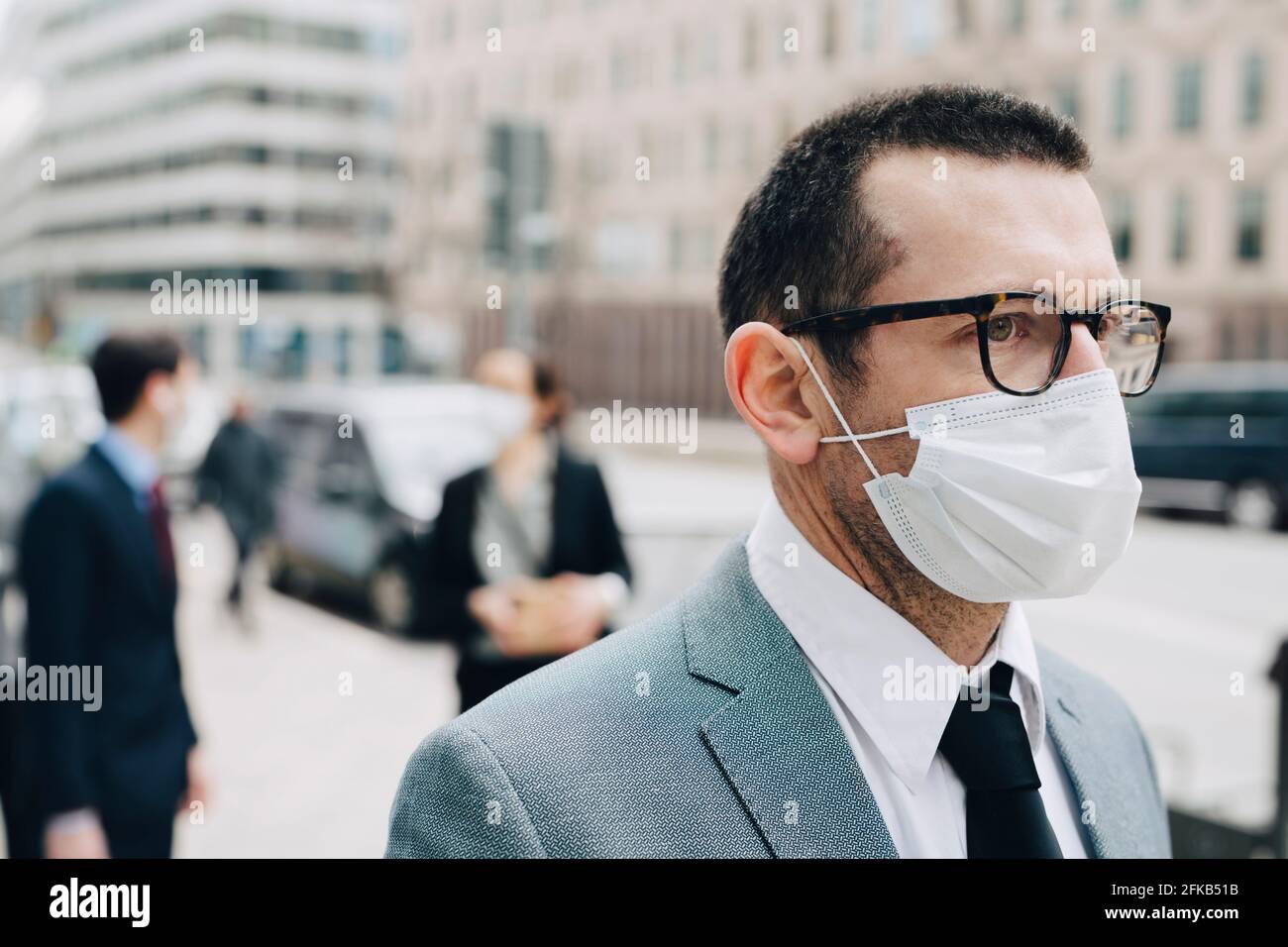 Reifer Geschäftsmann mit schützender Gesichtsmaske in der Stadt Stockfoto