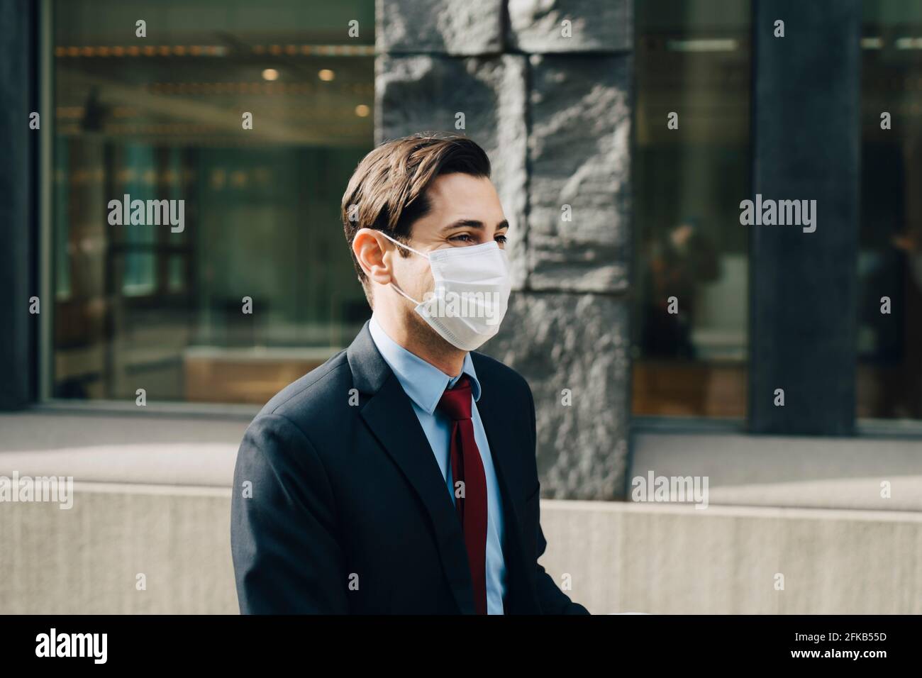 Geschäftsmann mit schützender Gesichtsmaske beim Bürogebäude Stockfoto