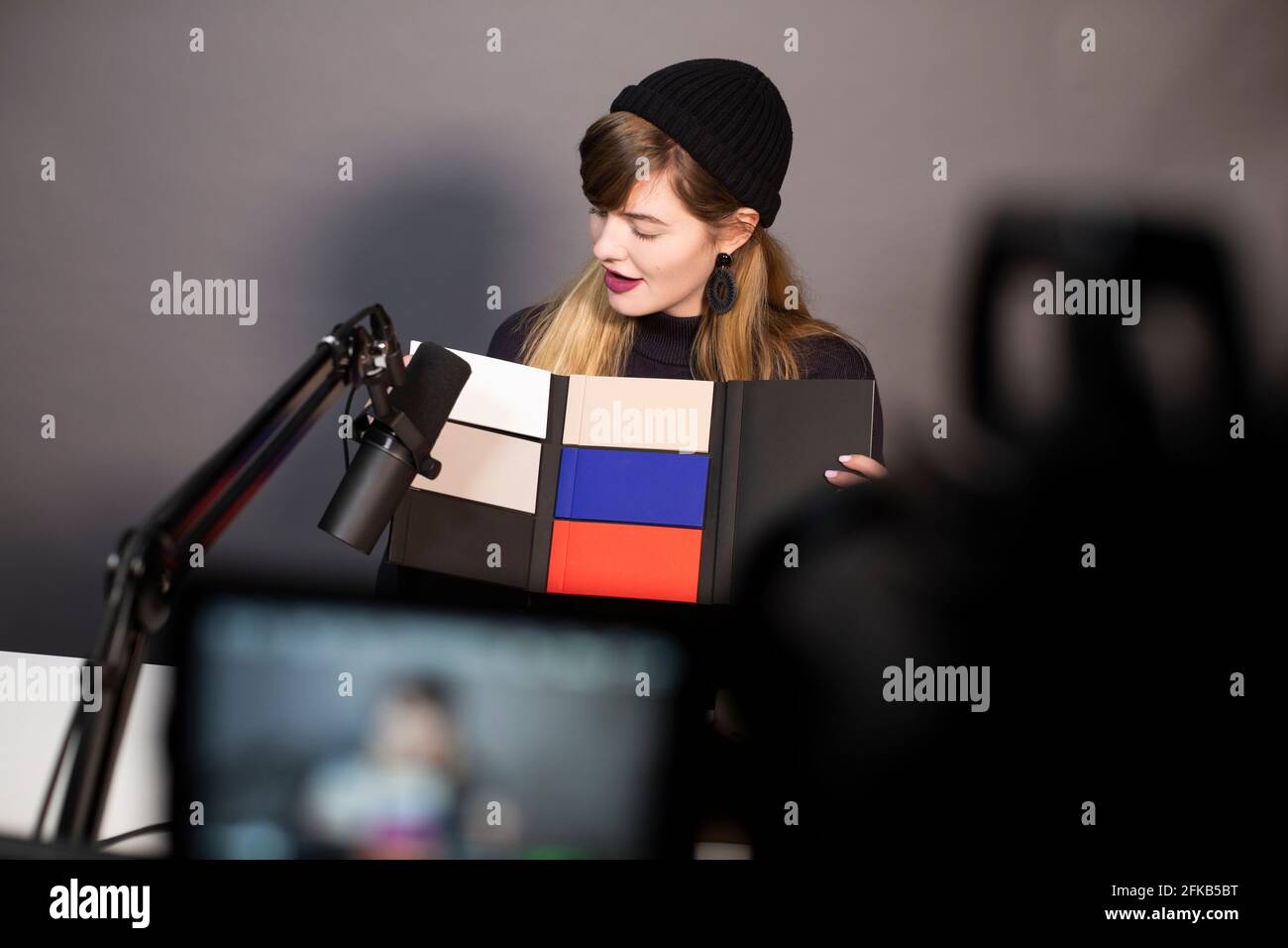 Geschäftsfrau, die sich das Produkt ansieht, während sie über eine Fernsehkamera aufzeichnet Stockfoto