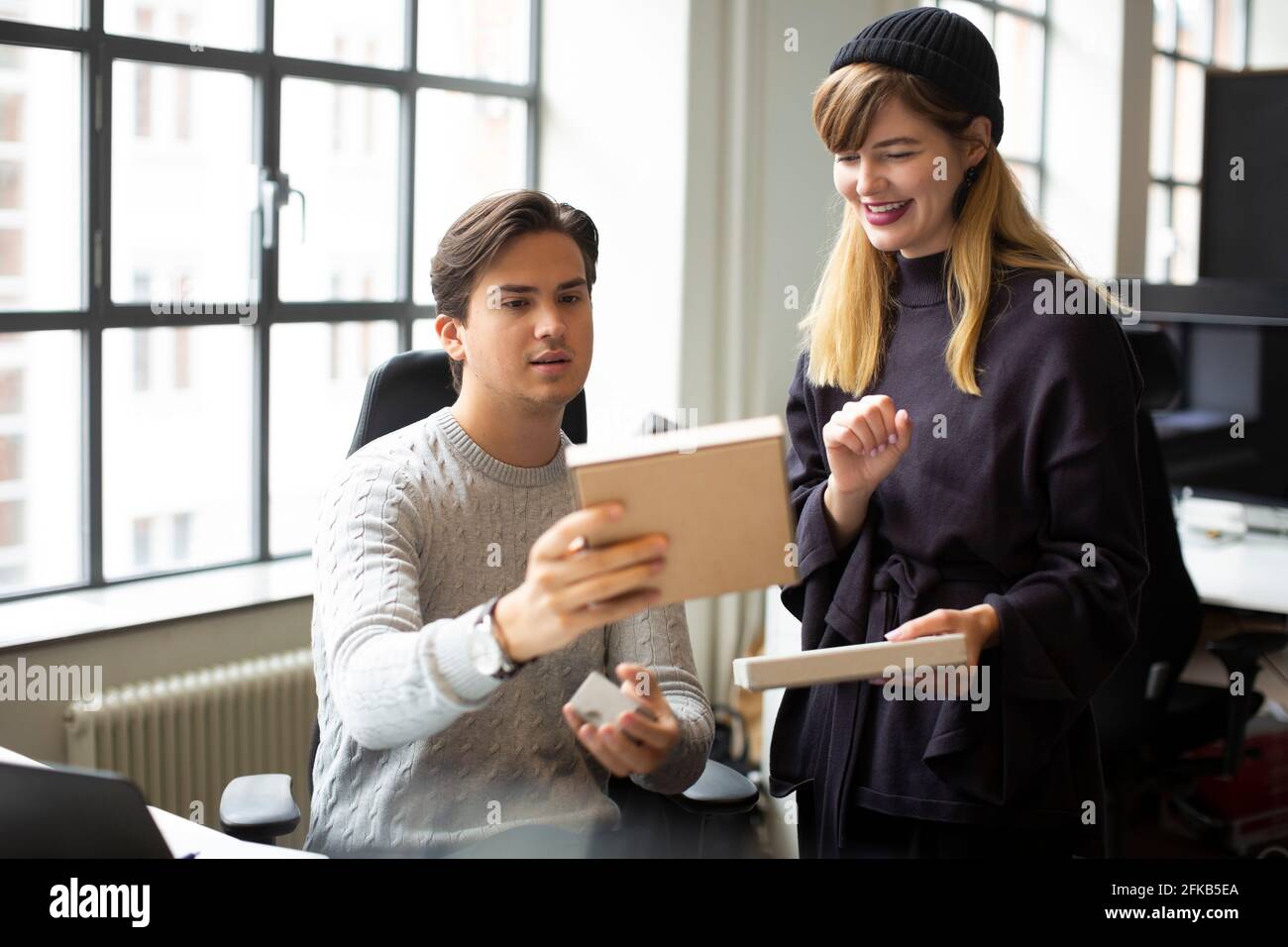 Lächelnde Unternehmerin, die mit einem männlichen Kollegen über das Produkt diskutiert Kreatives Büro Stockfoto