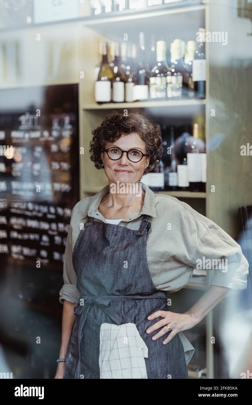 Porträt einer lächelnden Geschäftsbesitzerin mit der Hand auf der Hüfte Im Feinkostladen Stockfoto