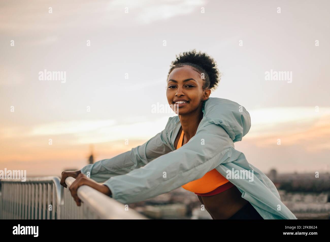 Porträt einer Sportlerin, die sich am Geländer gegen den Himmel lehnt Stockfoto
